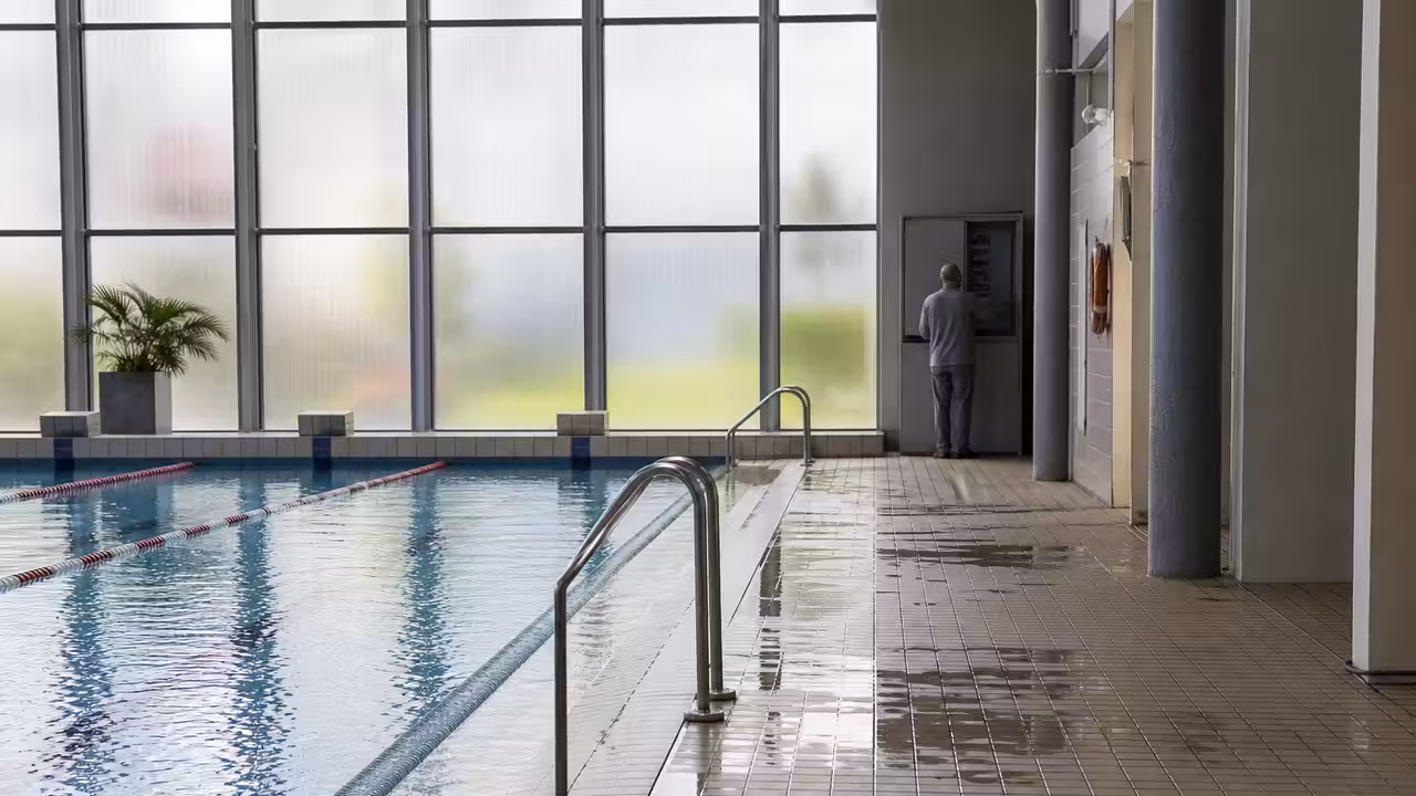 Bassin de natation couvert vide, lignes d’eau en place et lumière naturelle après une maintenance technique