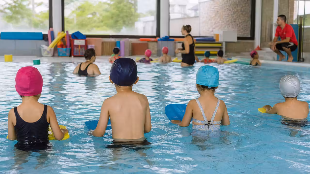 Groupe d’enfants de maternelle encadrés au bord d’un petit bassin pendant une séance de piscine scolaire