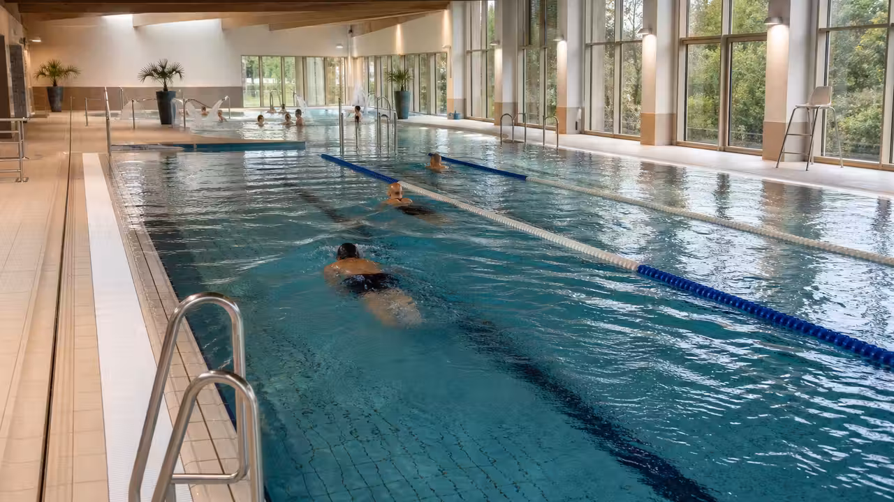 Bassin de 25 mètres d’une piscine municipale rénovée, avec lignes d’eau et baies vitrées lumineuses