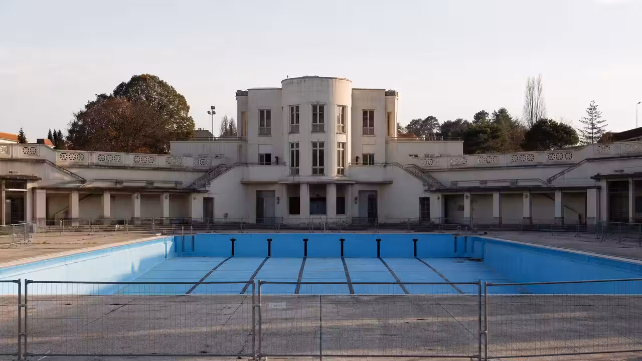 Piscine publique Art déco à Toulouse avec bassin extérieur, plages rénovées et façade patrimoniale en arrière-plan