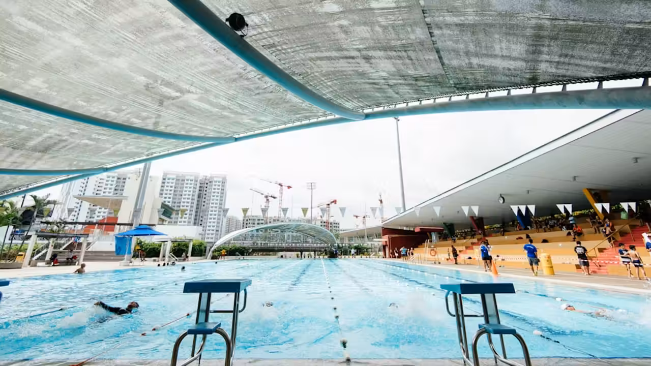 Piscine municipale couverte avec toiture vitrée, plages de bassin carrelées et zones de travaux sécurisées