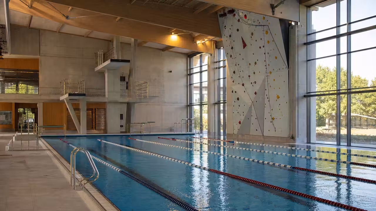 Bassin sportif couvert de 25 mètres avec lignes d’eau, plongeoir et mur d’escalade au-dessus de l’eau