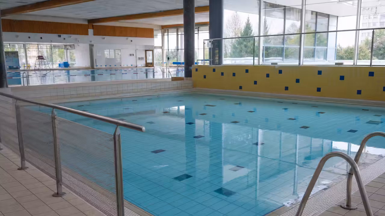 Bassin intérieur de piscine municipale temporairement fermé, avec lignes d’eau et signalisation discrète au bord
