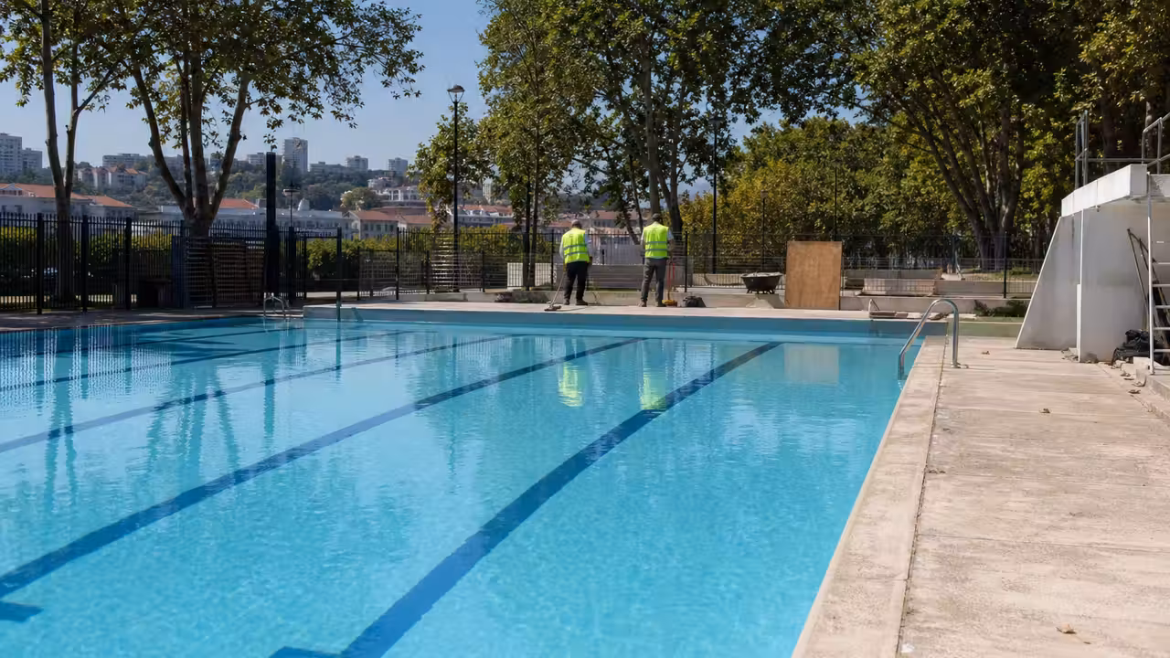 Bassin extérieur d’un centre nautique urbain avec lignes d’eau et zones ombragées lors d’une forte chaleur