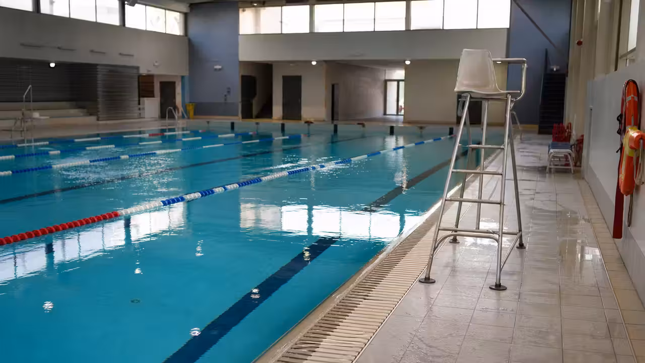 Bassin intérieur municipal vide avec fauteuil de surveillance et lignes d'eau prêtes avant la réouverture