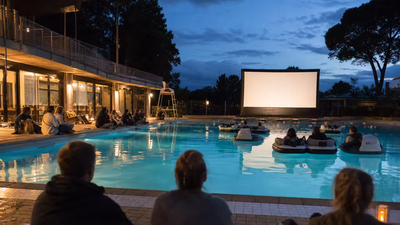 Projection nocturne dans un bassin couvert avec sièges flottants et spectateurs vus de dos