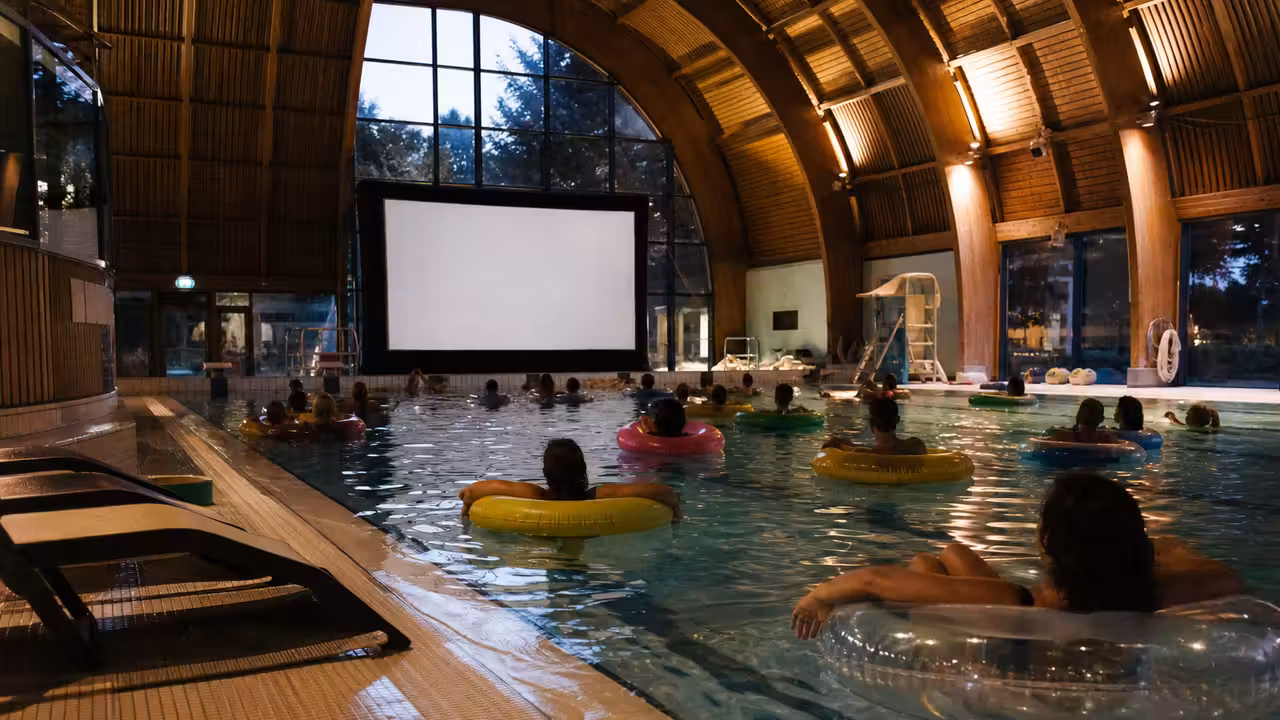 Spectateurs installés sur des bouées dans un bassin devant un écran gonflable de projection