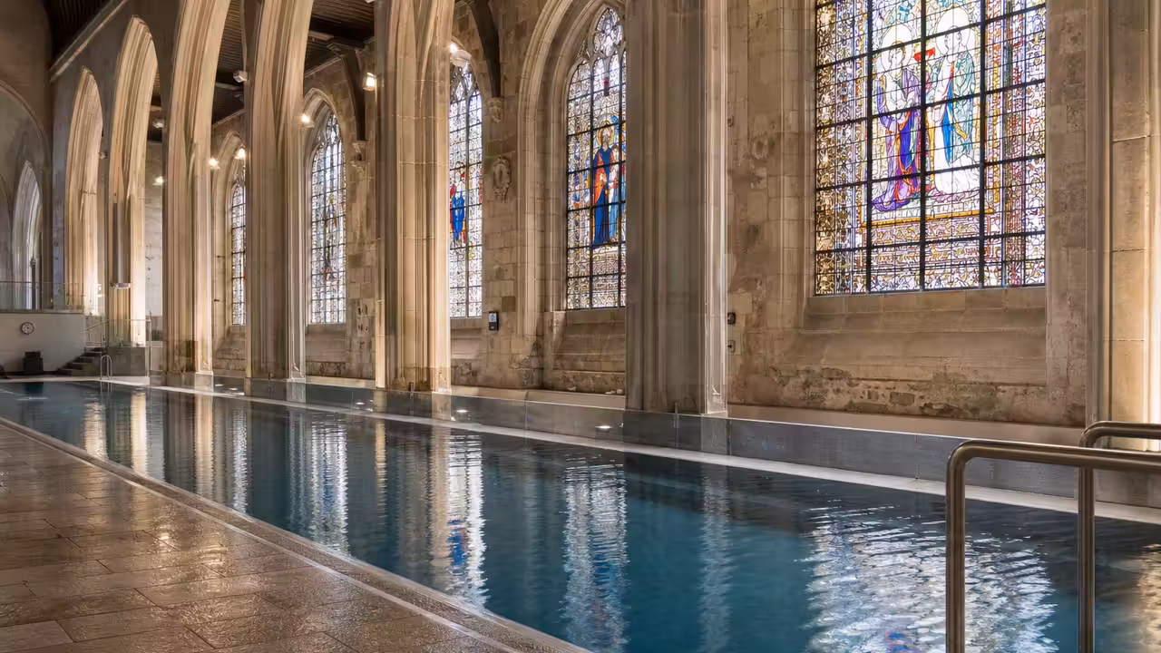 Nef d’une ancienne église européenne reconvertie en piscine municipale lumineuse avec bassin et vitraux préservés