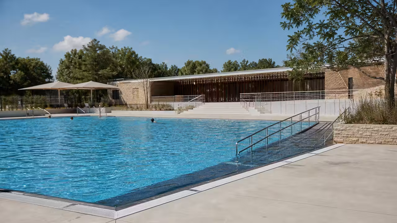 Piscine publique extérieure rénovée avec bassin, plages minérales, vestiaires et espaces ombragés en été