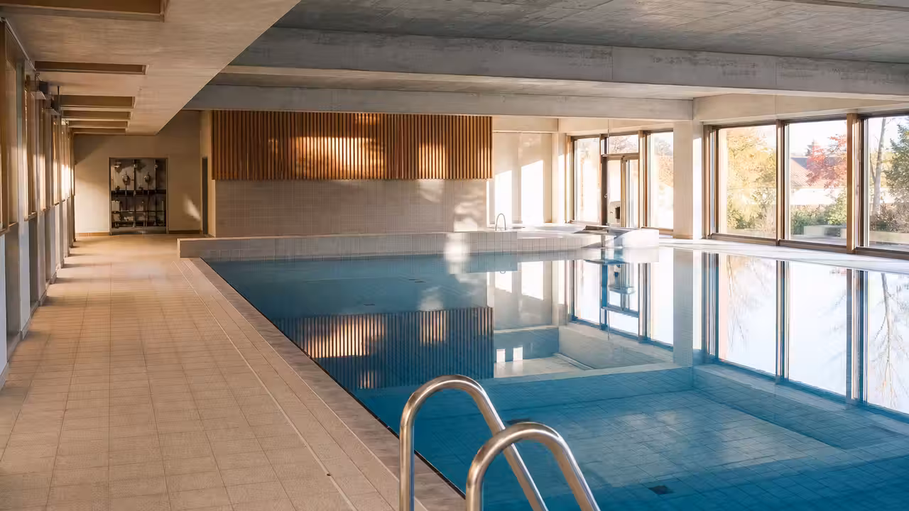 Entrée d'une piscine publique rénovée avec bassin intérieur et installations techniques remises en service
