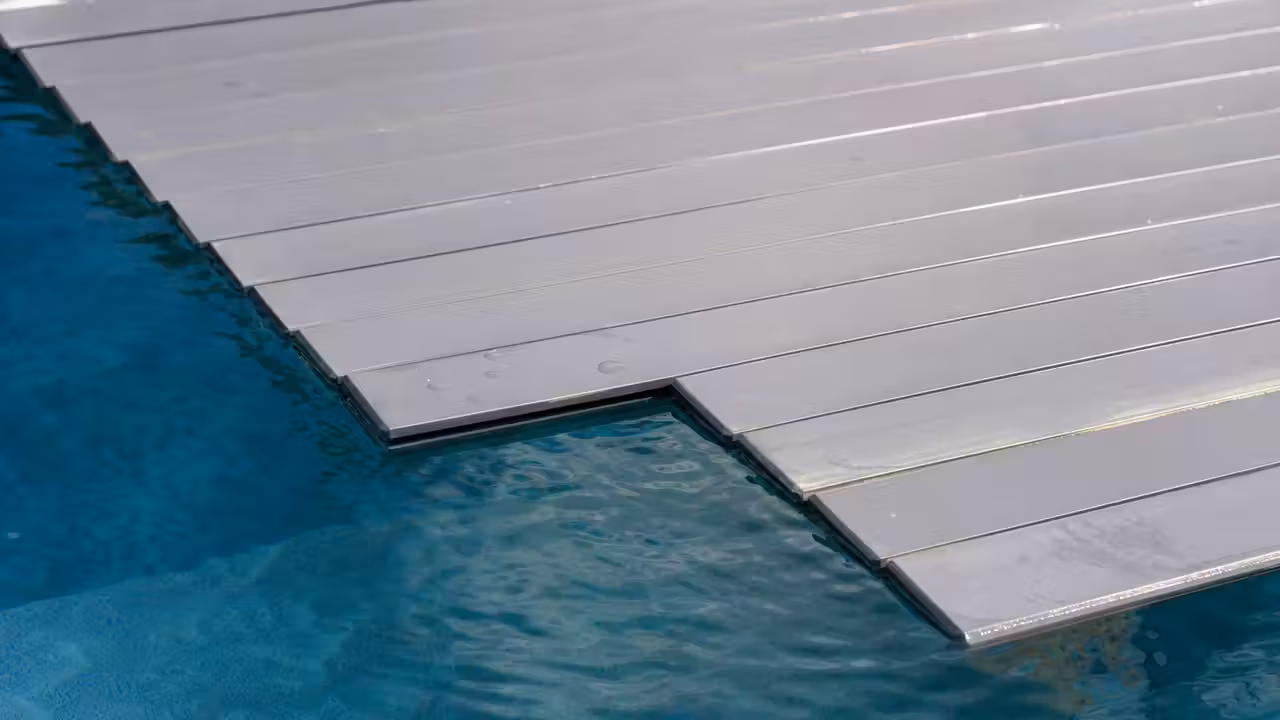 Tablier de volet immergé de piscine partiellement déroulé à la surface de l'eau, avec une lame légèrement affaissée
